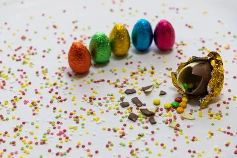 Broken golden chocolate easter eggs with colorful chocolates inside on white  Stock Photos