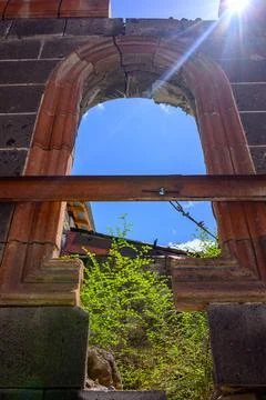 Broken Gothic archway framed by sun and greenery Stock Photos