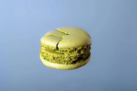 Broken green macaroon on a blue background Stock Photos