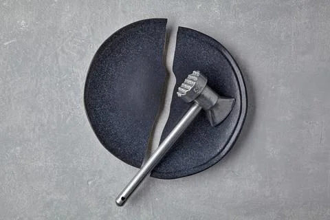 Broken grey ceramic plate and chopping mallet on grey stone background. top.. Stock Photos