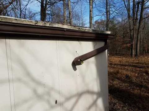 Broken gutter downspout on shed in forest or woods Stock Photos