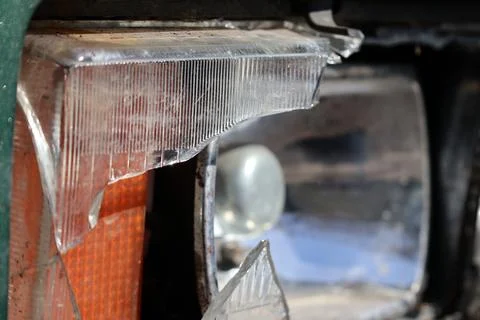 Broken Headlight Shows Damage on a Car Parked Near a Busy Street in the Aft.. Stock Photos