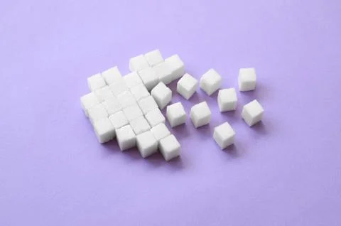 A broken heart made of sugar cubes lies on a trendy pastel violet background Stock Photos