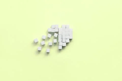 A broken heart made of sugar cubes lies on a trendy pastel lime Stock Photos