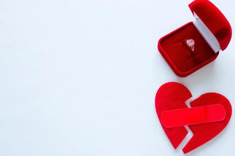 Broken heart with a patch and a wedding ring on a white background with space Stock Photos