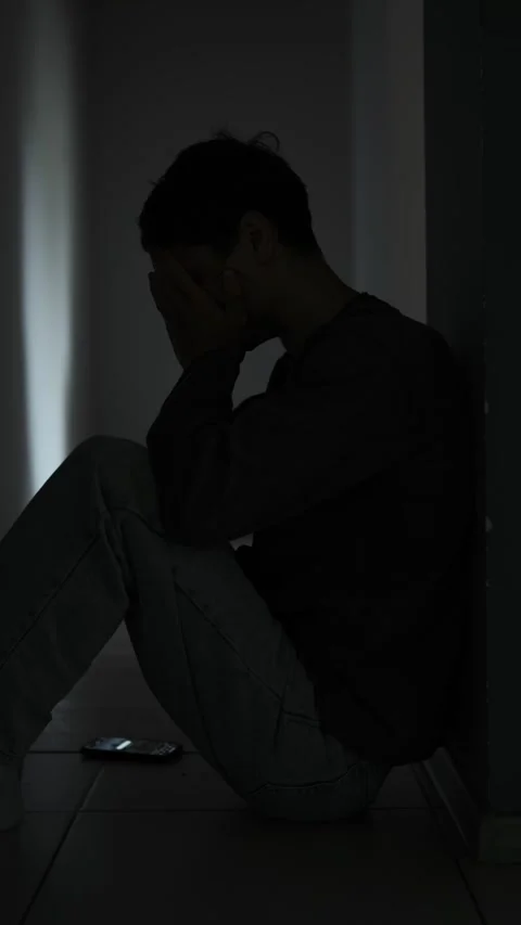Broken hearted man sitting alone in dark room after breakup. Vertical video Stock Footage 313880124