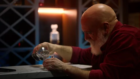 Broken-hearted middle-aged man pours liquor into glass after divorce at home Stock Footage 346714172