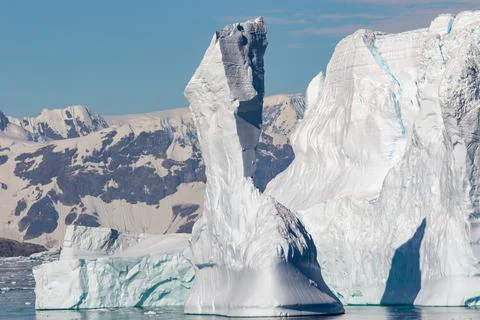 A broken high iceberg with mountains in the background in Antarctica. Global  Stock Photos