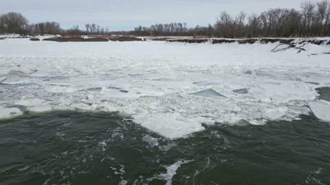 Broken ice pieces at edge of a flowing river in the winter with snow and trees Stock Footage 235727593