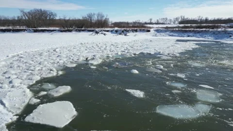 Broken ice pieces at edge of a flowing river in the winter with snow and trees Stock Footage 235727645