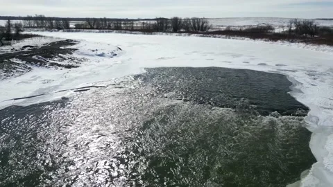 Broken ice pieces at edge of a flowing river in the winter with snow and trees Stock Footage 235727659