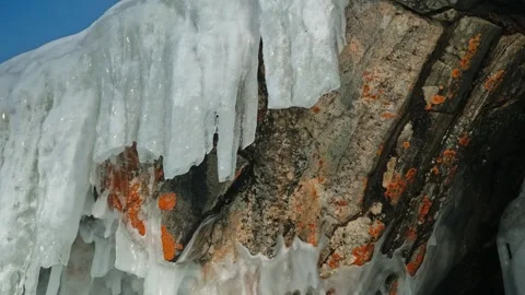 The broken off icicles flowing down from the rocks, illuminated by the sun. On Stock Footage 257768232