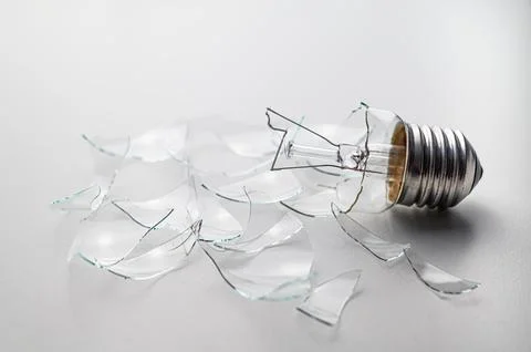 Broken light bulb, on white surface. Stock Photos