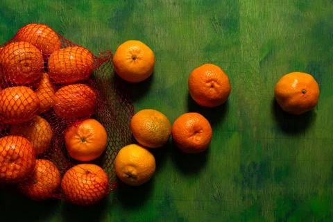 Broken mesh bag of oranges on an old wooden background in shades of green wit Stock Photos