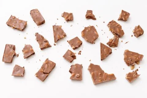Broken milk chocolate pattern, top view flat lay on background Stock Photos