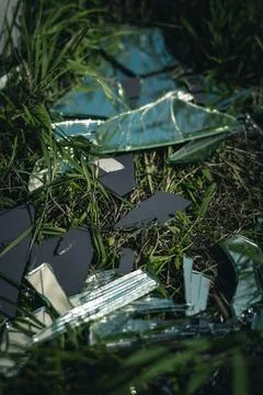 A broken mirror, lying in pieces on the grass, next to the road Stock Photos