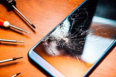 A broken mobile phone with a broken screen with tools, Foto stock