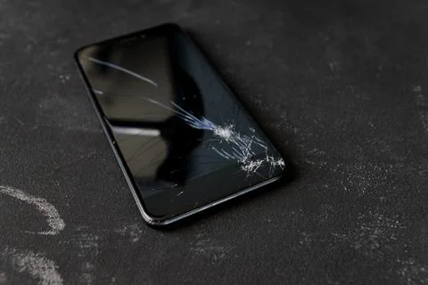 Broken mobile phone display with a big black iron hammer in the screen. Stock Photos