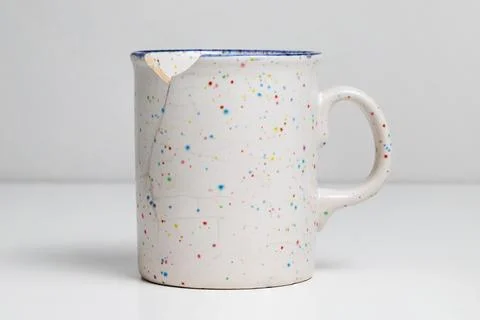 Broken mug on white table. Cracked cup Stock Photos