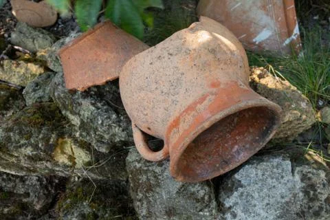 A broken old clay pitcher rests on the stones. Stock Photos