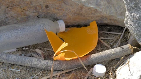 The broken orange plastic and the bottle on the shore of Pacific Ocean Stock Footage 129024523