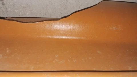 Broken orange terracotta roof tile showing a sharp jagged edge Stock Photos
