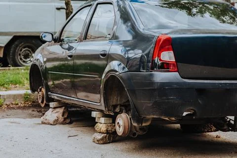 A broken passenger car without wheels stands on bricks Stock Photos