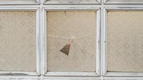 Broken patterned vintage window pane in a white wooden frame. Stock Photos