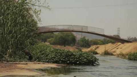 Broken pedestrian bridge over a storm water canal with filthy running Vídeos de archivo 95339213