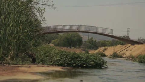 Broken pedestrian bridge over a storm water canal with filthy running Vídeos de archivo 95341474