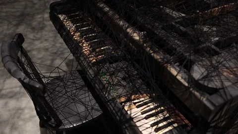A broken piano entangled in black threads, symbolizing the end of a pianist’s ca Stockbeeldmateriaal 304357456