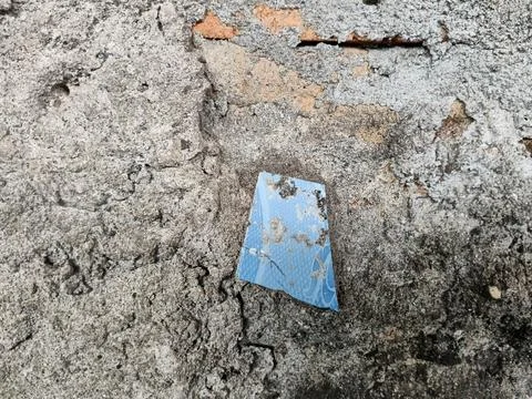 Broken piece of blue ceramic tile stuck on weathered concrete wall Stock Photos