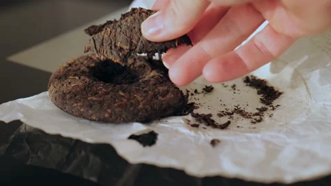 A broken piece of pressed dark shu pu-erh in a man's hand. Chinese tea Stock Footage 218447402