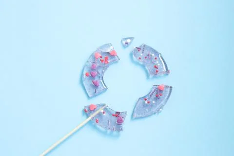 Broken in pieces candy on a stick. Smashed lollipop on blue background. Top v Stock Photos