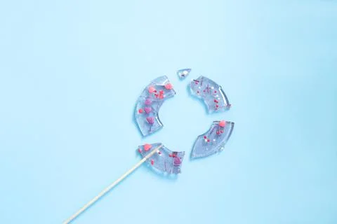 Broken in pieces candy on a stick. Smashed lollipop on blue background. Top v Stock Photos