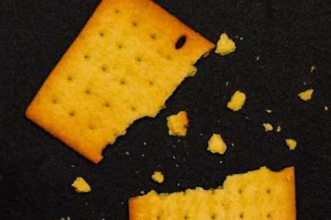 Broken Pieces of Crispy Wheat Cracker with Crumbs on Black Background, Clos.. Fotos de archivo