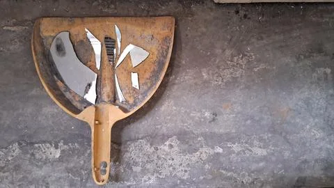 Broken pieces of mirror resting inside a dirty yellow dustpan Stock Photos