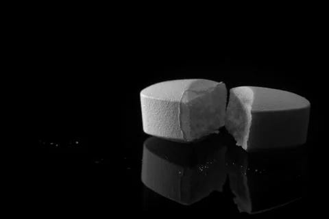 Broken pill dosage macro on black background Stock Photos
