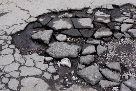 Broken pit with pieces of asphalt. Bad asphalt road. Destruction of roads, pi Stock Photos
