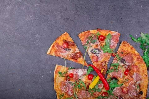 Broken pizza slice with vegetables and cheese on dark surface Stock Photos