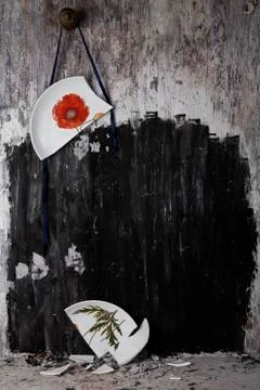 Broken plate hanging from string on wall Stock Photos