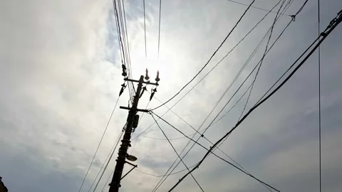 Broken power lines swaying in wind with bright sun in background Stock Footage 245059712