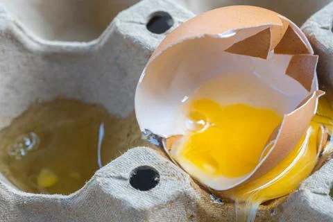 Broken Raw Egg Spilling onto a Cardboard Egg Tray Stock Photos