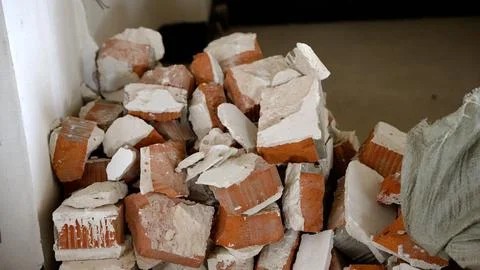 Broken red bricks and white plaster debris pile in construction corner Stock Photos