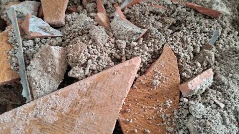 Broken red clay tile shards scattered throughout rough construction debris Stock Photos
