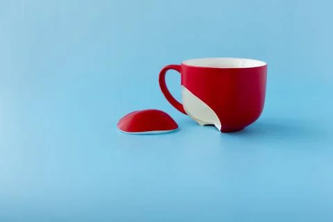 Broken red cup on blue background, symbol of divorce, loss Stock Photos