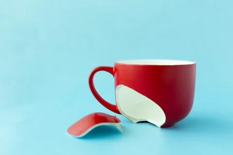 Broken red cup on blue background, symbol of divorce, loss Stock Photos