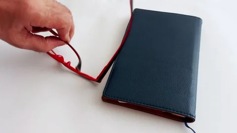 Broken Red Glasses Rest Quietly Beside a Blue Book in Morning Light Stock Footage 313117311