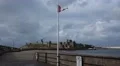 Broken red Isle of Man flag waving in the wind in front of Peel castle HD Footage