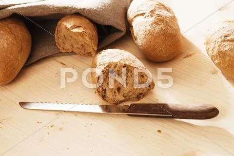 Broken rye bun with a knife Stock Photos